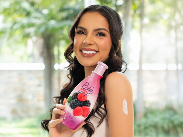 Mujer sonriente usando loción corporal LêCleire de frutos rojos